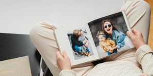 A mom holding a baby photo book on her lap.